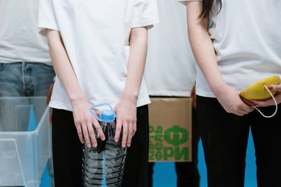 Young adults holding recyclable materials and containers, promoting environmental awareness.